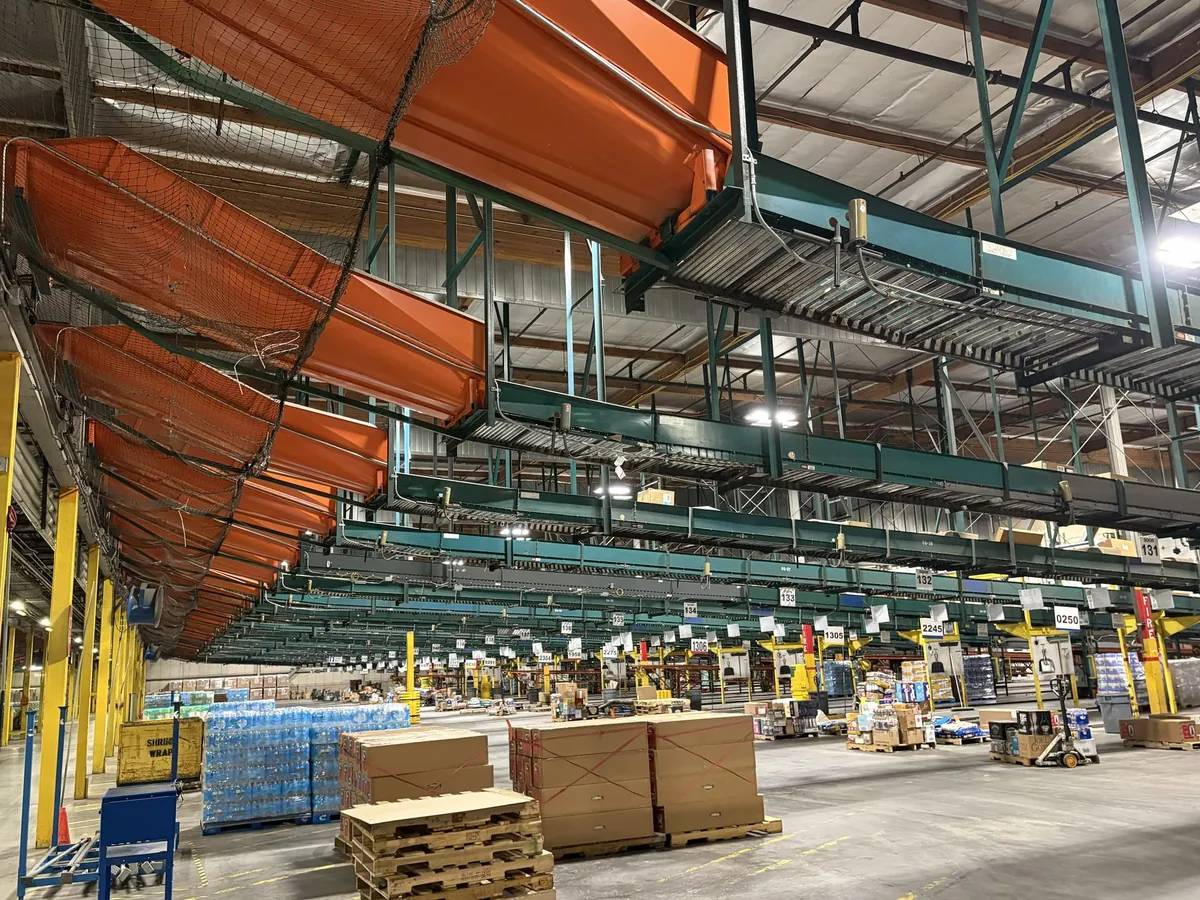 Orange overhead chutes above warehouse conveyors