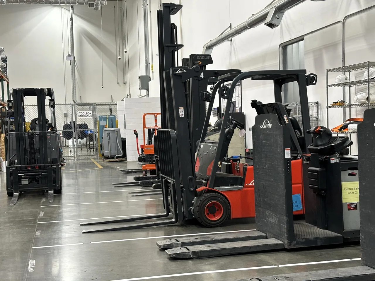 Electric warehouse forklifts parked inside an industrial building