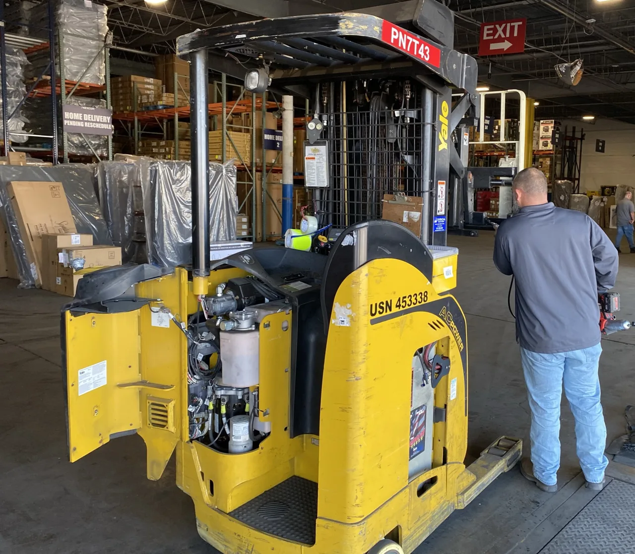 Technician beside a forklift with its service compartment open